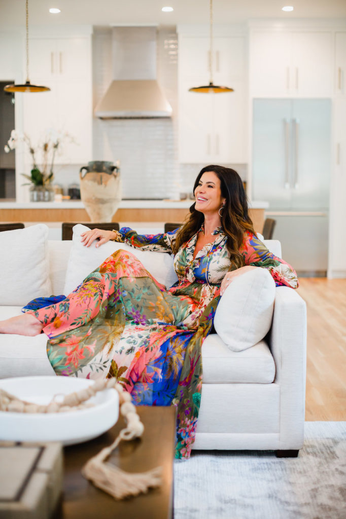 Woman in bright patterned maxi dress lounging on a couch inside of a luxury real estate listing in Raleigh NC