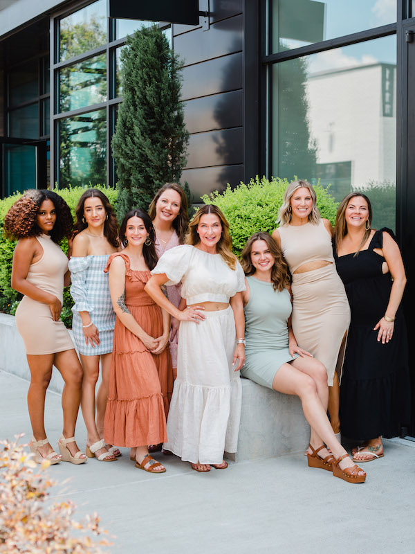Beauty Co. team in Raleigh poses outdoors in front of a modern building for a team photo session | Sara Coffin Photography