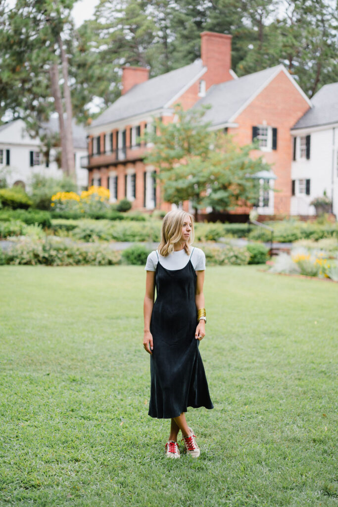 Girl in a black slip dress poses on the lawn in front of the Weymouth Center in Southern Pines NC | Photo by Sara Coffin Photography