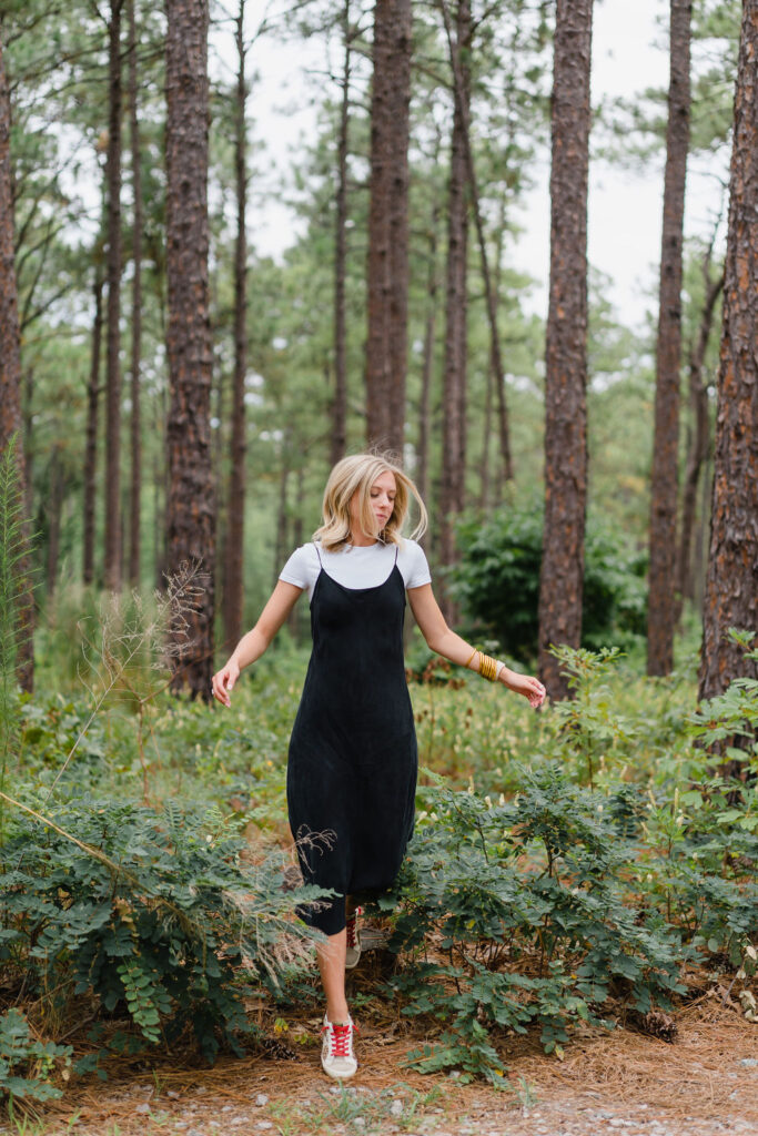 Girl in a black slip dress runs through Weymouth Woods in Southern Pines NC | Photo by Sara Coffin Photography