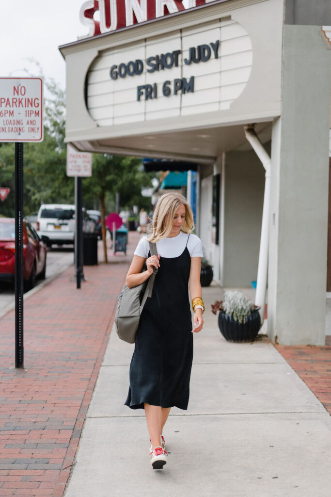Girl in black slip dress walks past the Sunrise Theater in downtown Southern Pines