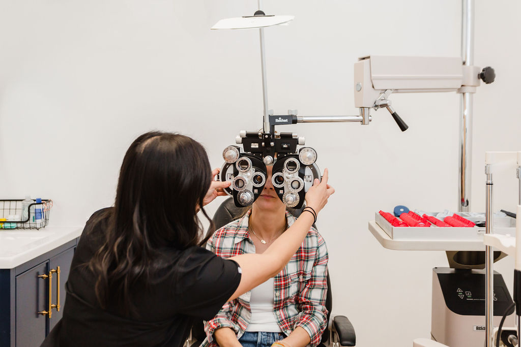 Eye doctor adjusts phoropter while client looks through lens to determine prescription | Business branding photography by Sara Coffin for The Vision Studio 