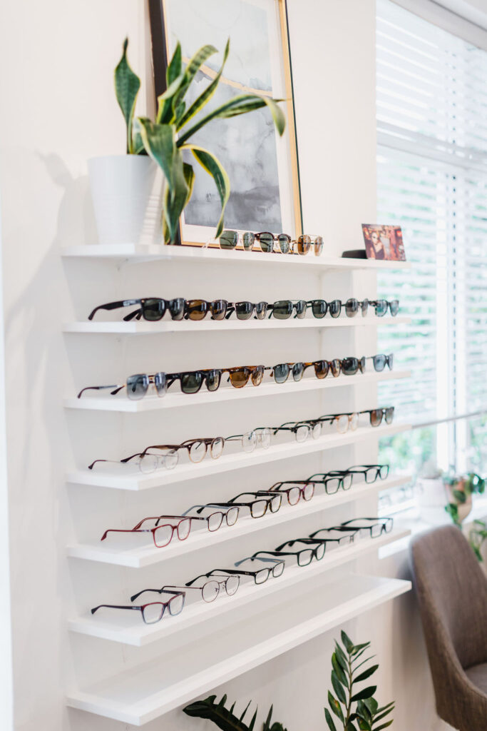 Five shelves hold pairs of designer glasses and sunglasses frames | Business branding photography by Sara Coffin for The Vision Studio 