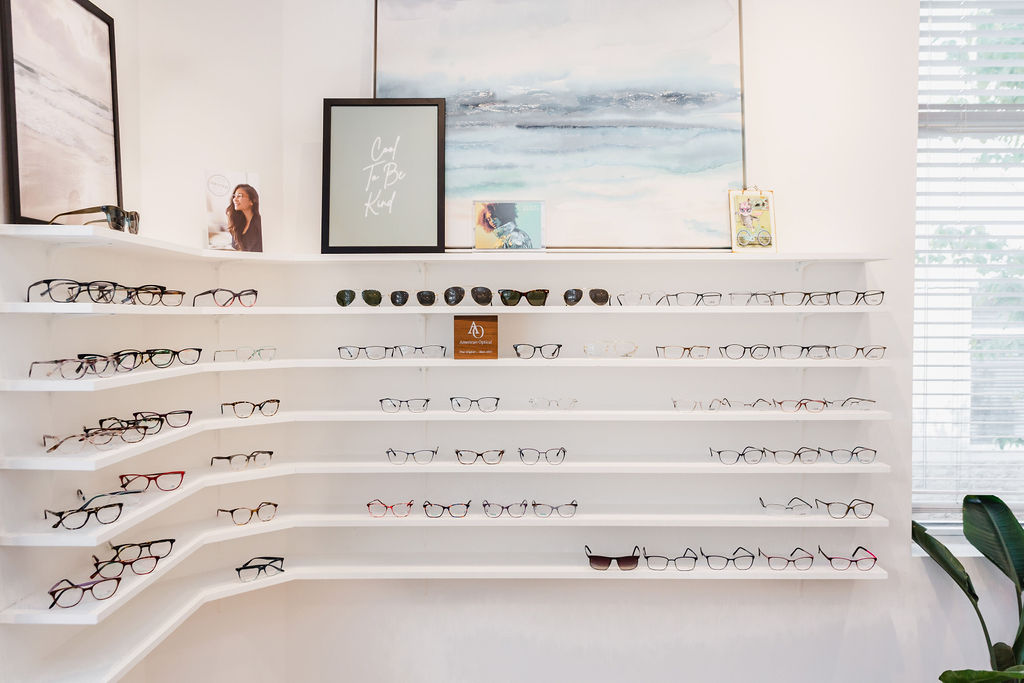 Six white shelves hold pairs of designer glasses frames | Business branding photography by Sara Coffin for The Vision Studio 