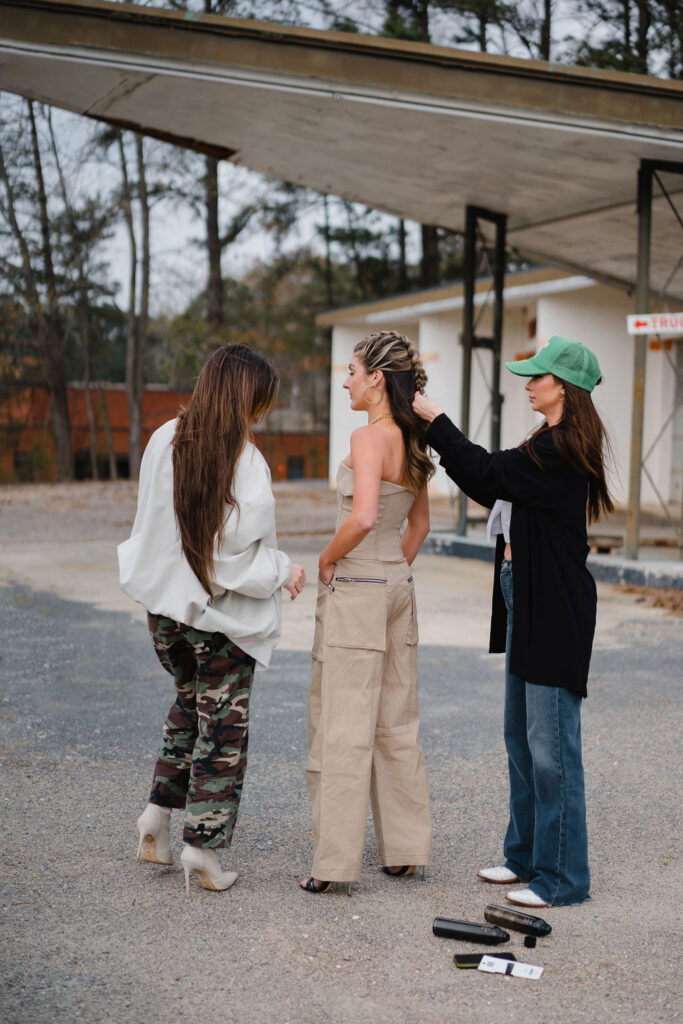Personal stylist and hairstylist simultaneously work to style a model on set during an outdoor photoshoot in downtown Sanford NC
