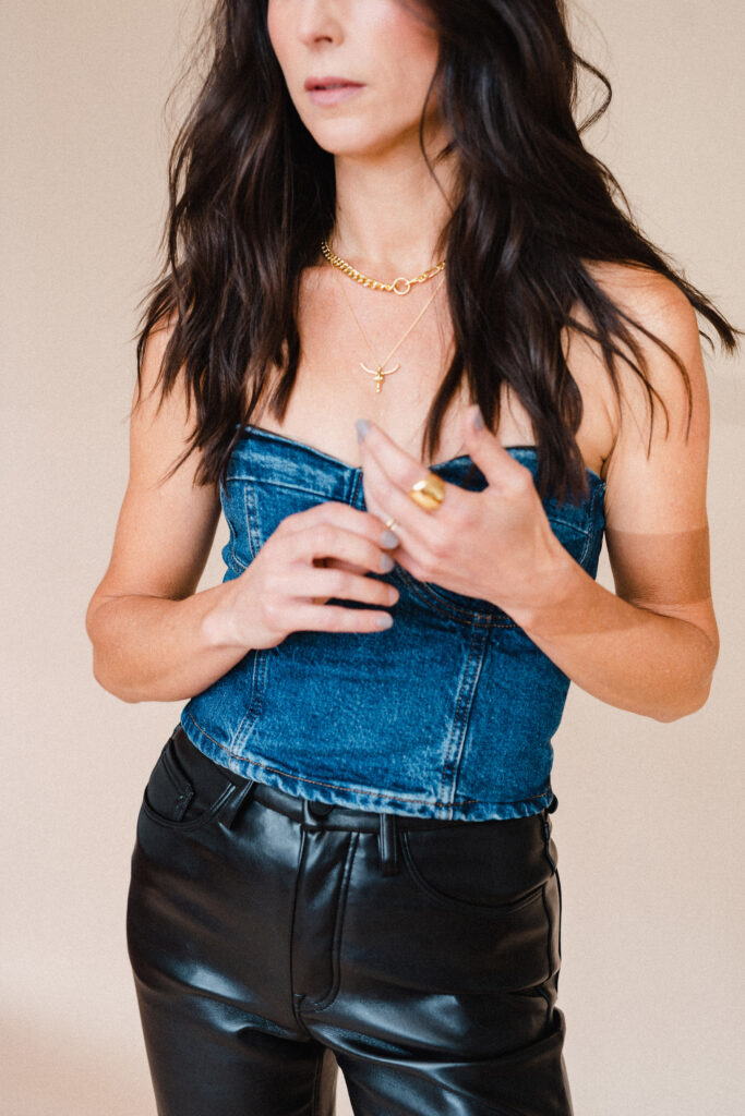 Sara Coffin wears denim corset shirt with black leather pants and simple gold jewelry during personal branding photo session