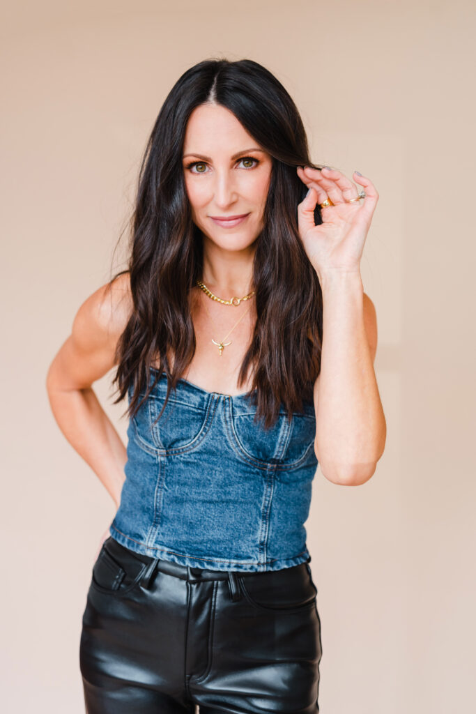 Sara Coffin wears denim corset shirt and black leather pants outfit for headshots during a photo studio photoshoot
