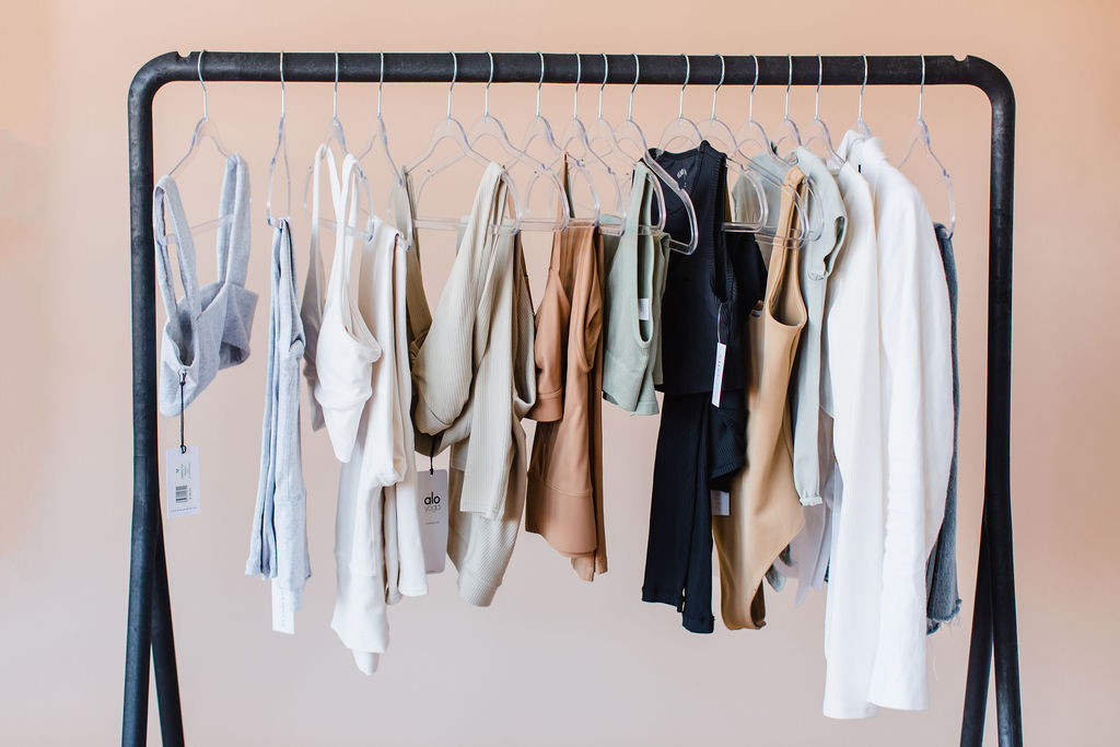 Black clothing rack holds various pastel colored workout clothes on hangers