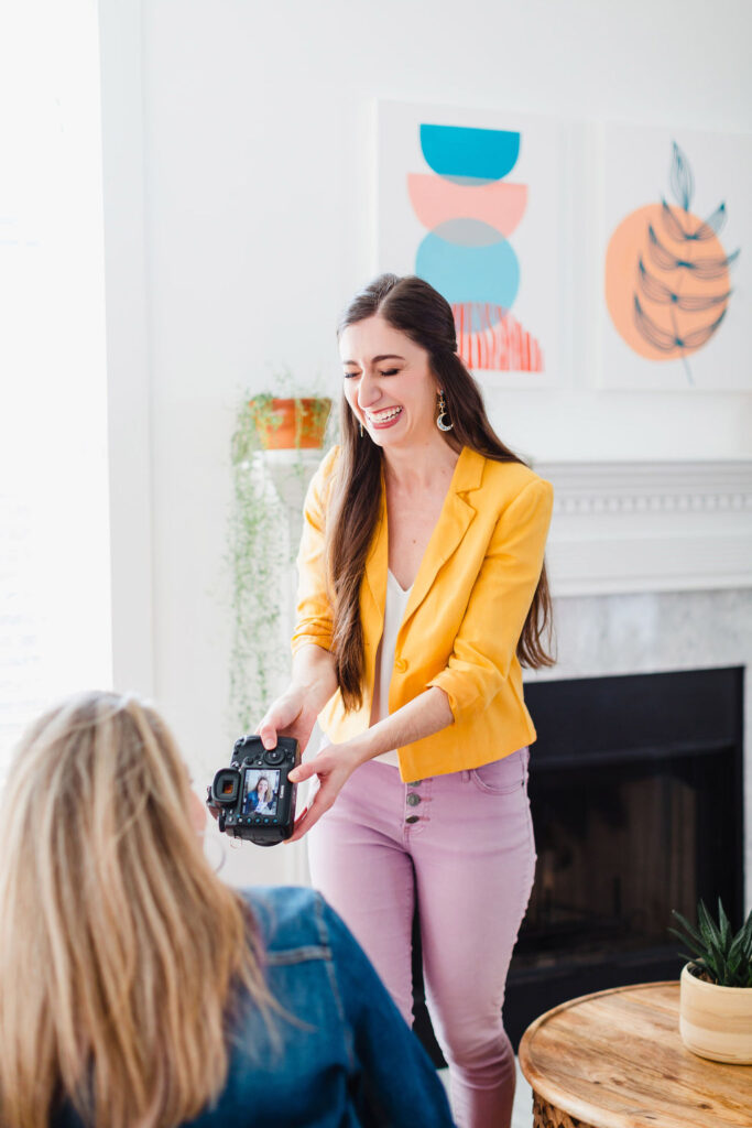 Photographer in bright yellow blazer shows a picture to her client on her camera | Personal branding photography session in Charleston, SC for Michelle Fiorello