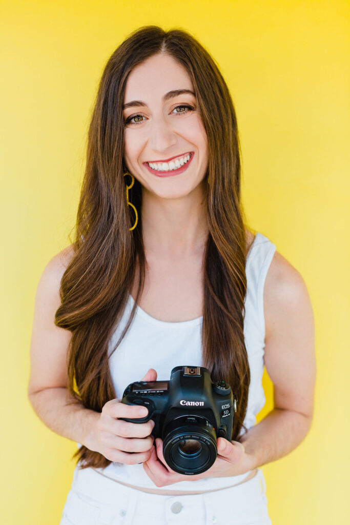 Photographer holds camera in front of a neon yellow backdrop | Personal branding photography session in Charleston, SC for Michelle Fiorello