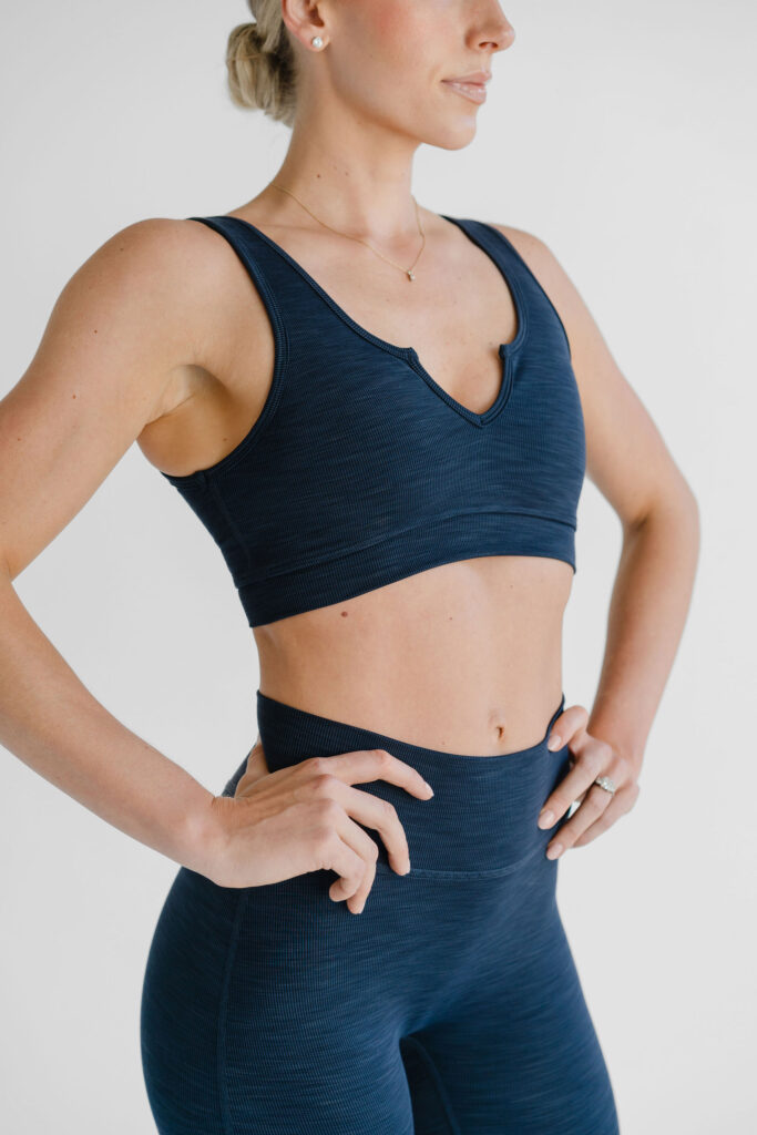 Girl in navy two-piece athletic wear set poses with hands on hips in front of a plain backdrop | Branding photos for K10 athletic brand by Sara Coffin Photo in NC