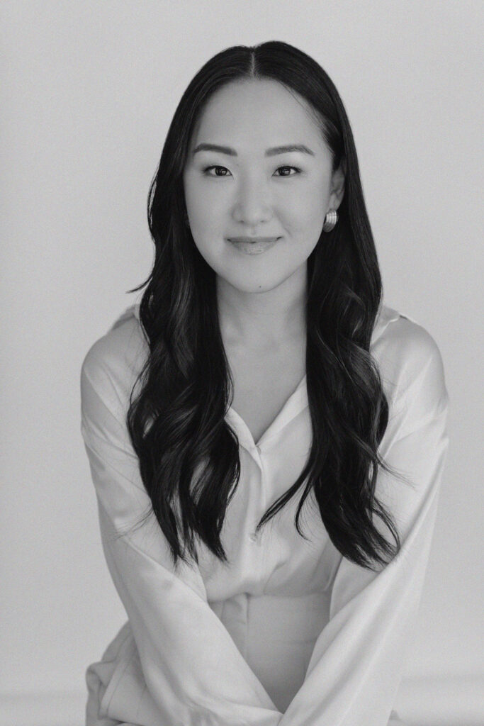 Black and white photo of an asian woman posing in front of a white backdrop wearing a white silk blouse | Sara Coffin Photo Headshot Mini Marathon session experience