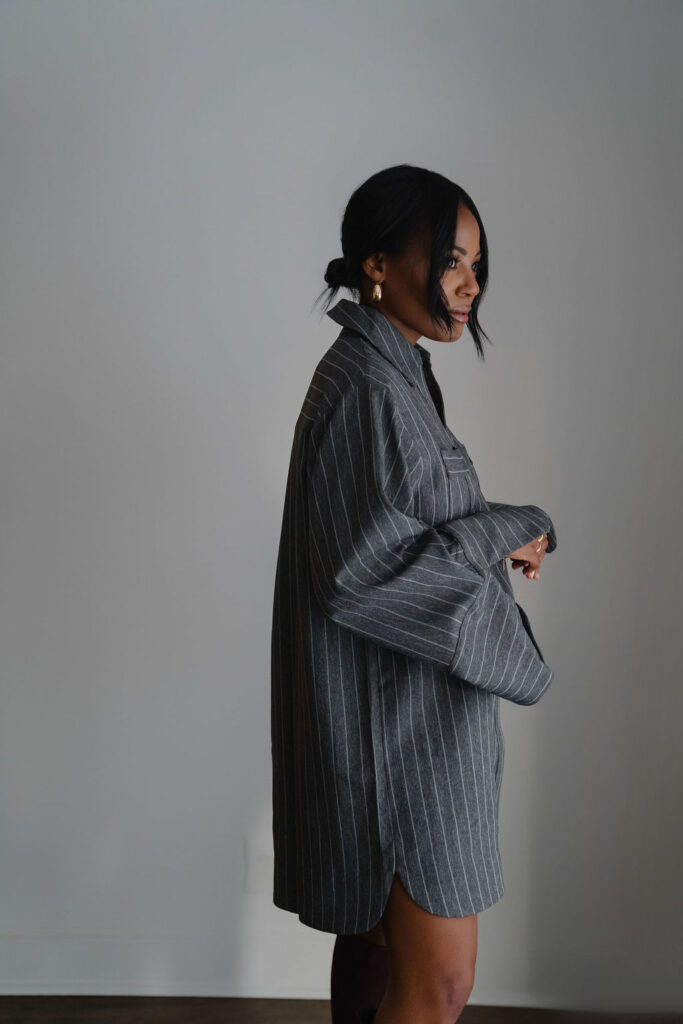 Side profile portrait of a black female entrepreneur wearing charcoal gray pinstripe oversized shirt dress inside a North Carolina photo studio | Sara Coffin Photo
