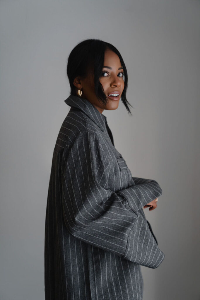 Close up side profile portrait of a black female entrepreneur wearing charcoal gray pinstripe oversized shirt dress inside a North Carolina photo studio | Portrait photography by Sara Coffin Photo