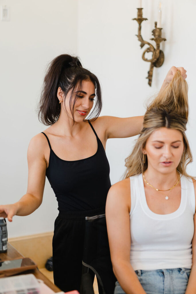 Makeup artist Sofia Brown of Styled By Sofia styles hair on a blonde woman sitting on a black makeup chair for a branding photoshoot with Sara Coffin Photo | Photoshoot Hair and Makeup tips